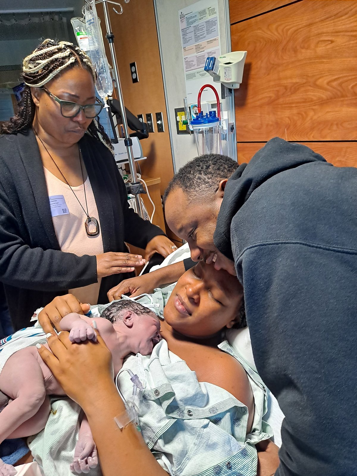 A doula with parents meeting their newborn at birth