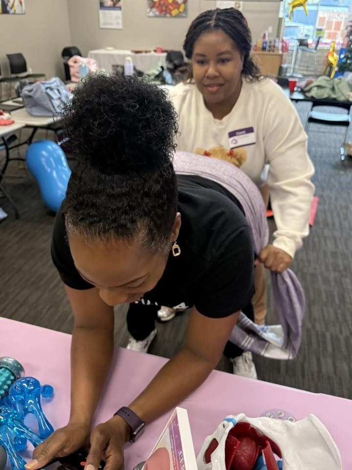 Two MHN doulas practicing rebozo at the training table